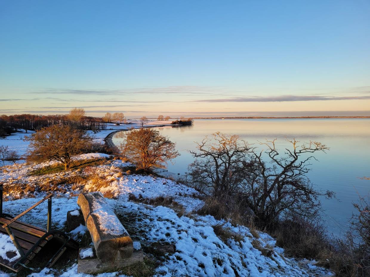 Blick auf die flache See an einem Winterabend, Schnee und rosa Himmel