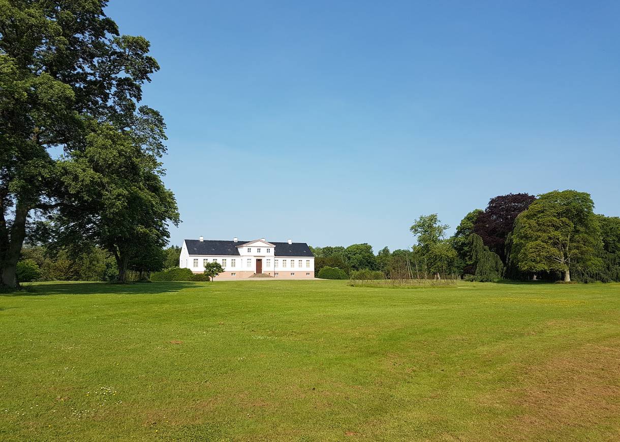 Weißes Gutshaus in einem weitläufigen Park