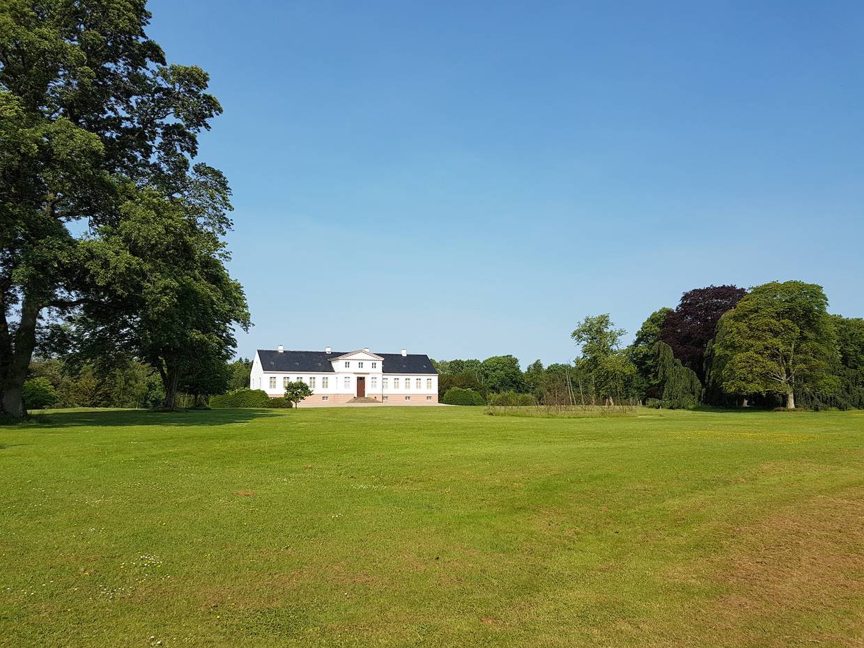 Weißes Gutshaus in einem weitläufigen Park