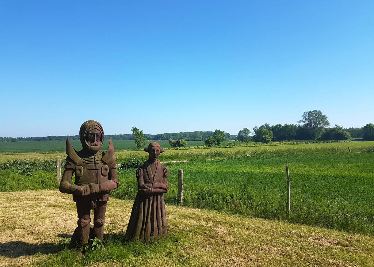 Zwei Holzfiguren auf einer Blumenwiese