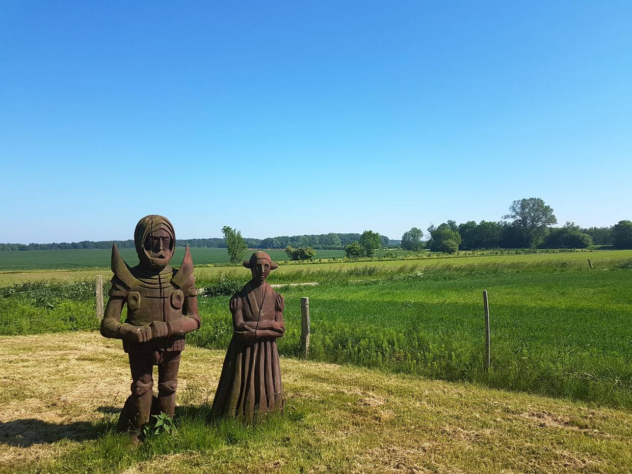 Zwei Holzfiguren auf einer Blumenwiese