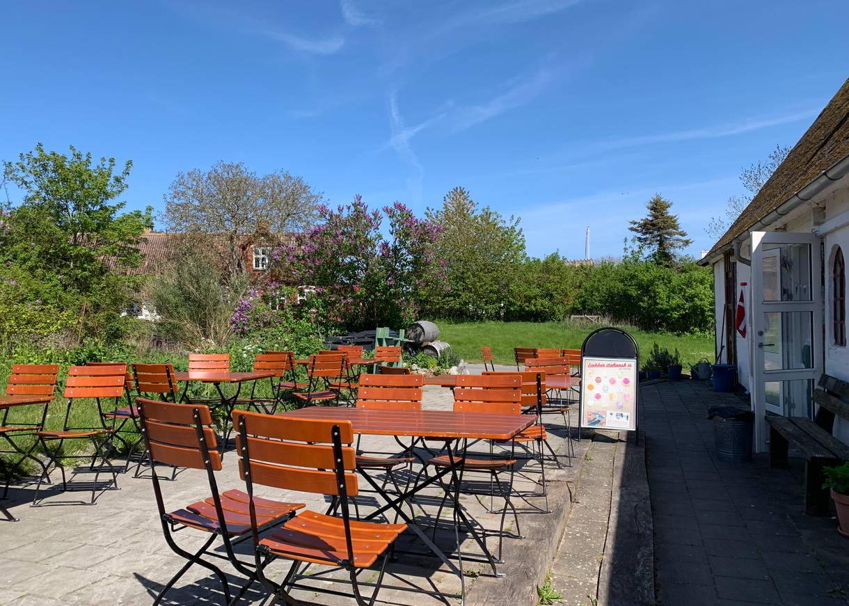 Terrasse mit vielen Sitzplätzen, dahinter ein blühender Garten