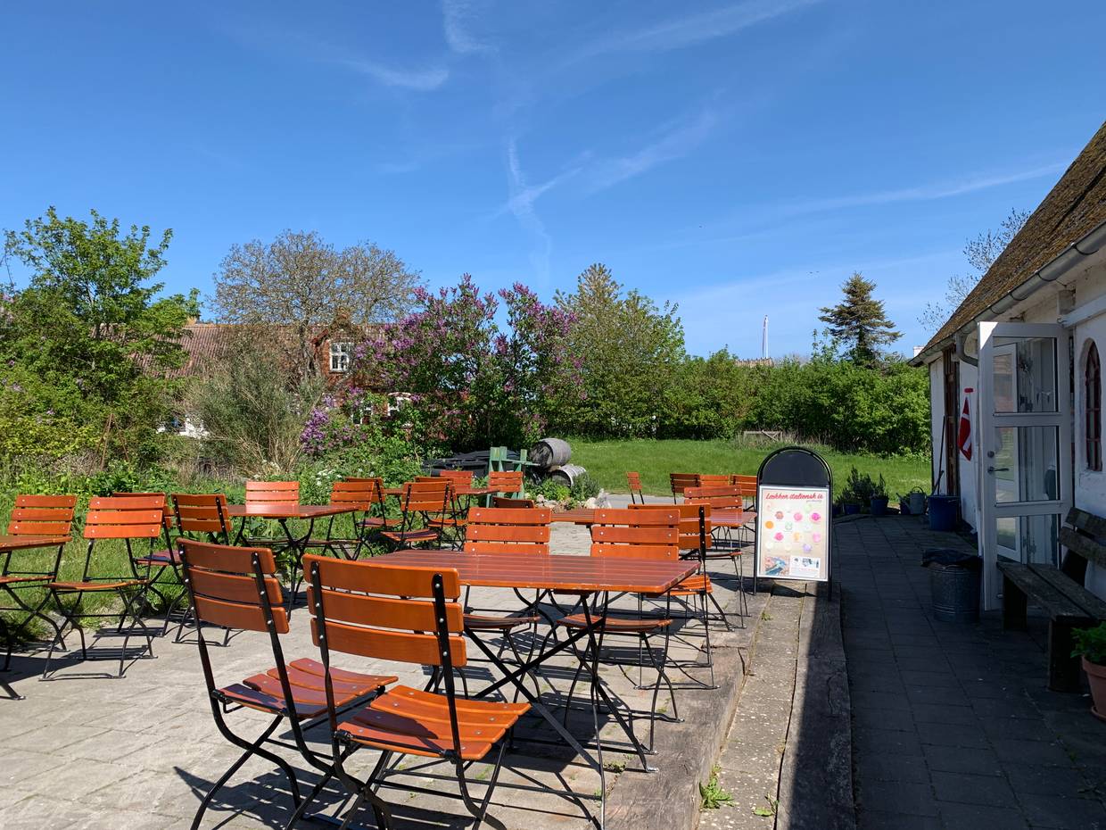 Terrasse mit vielen Sitzplätzen, dahinter ein blühender Garten