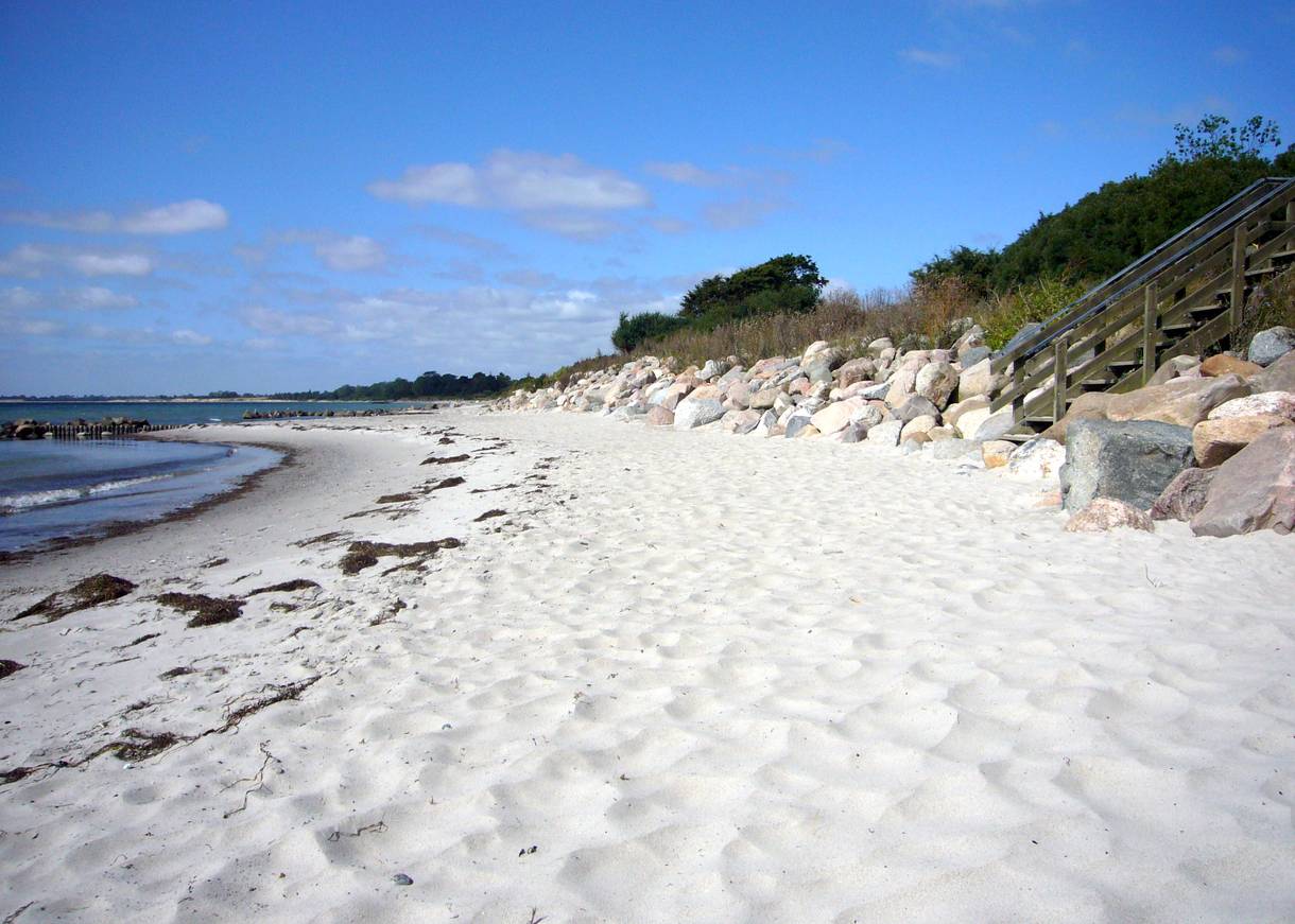 Sandstrand mit einer Treppe zwischen Feldsteinen