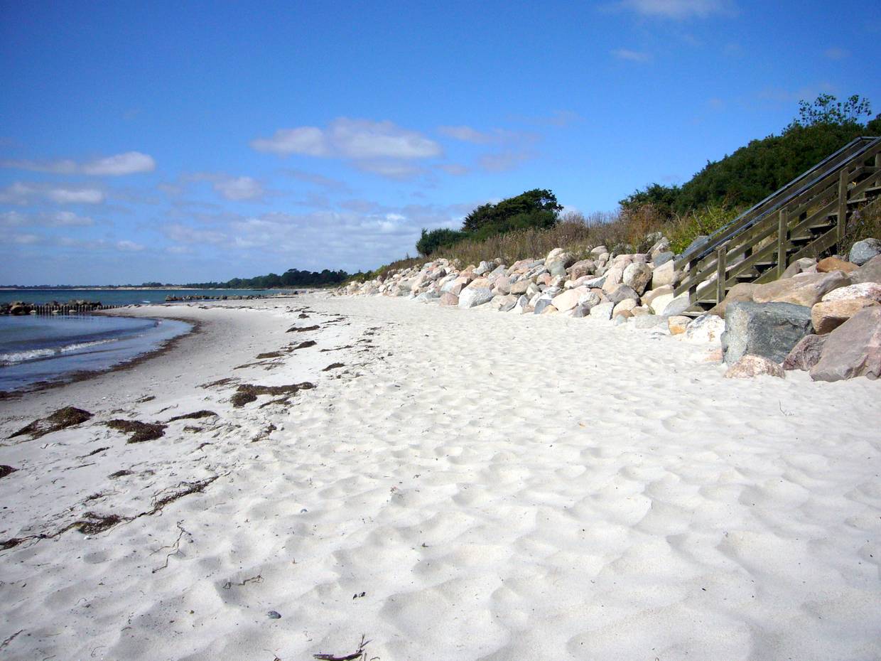 Sandstrand mit einer Treppe zwischen Feldsteinen