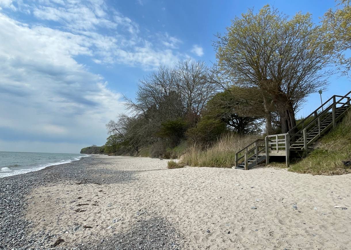 Holztreppe zum Strand, dahinter ein sehr kleines Haus