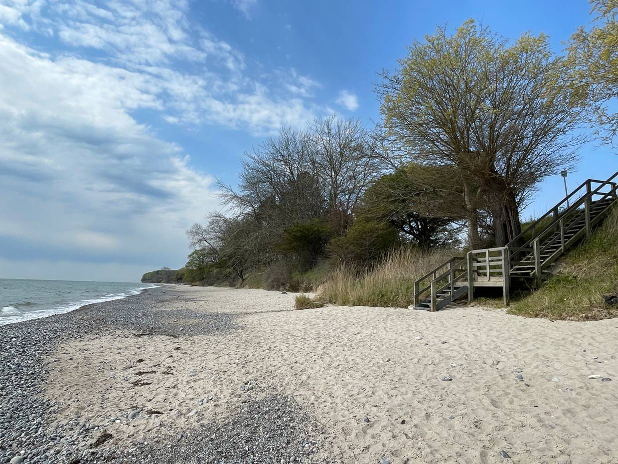 Holztreppe zum Strand, dahinter ein sehr kleines Haus