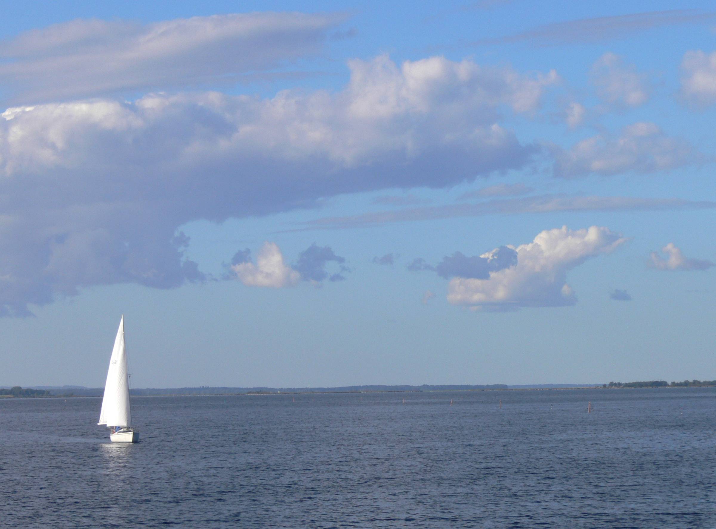 Großer See mit einem einzelnen Segelboot in der Mitte