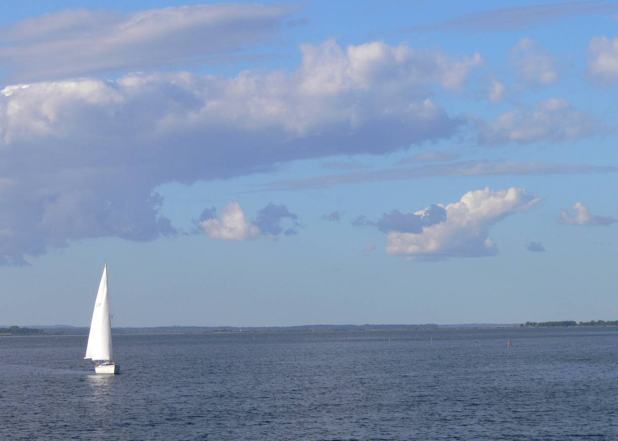 Großer See mit einem einzelnen Segelboot in der Mitte