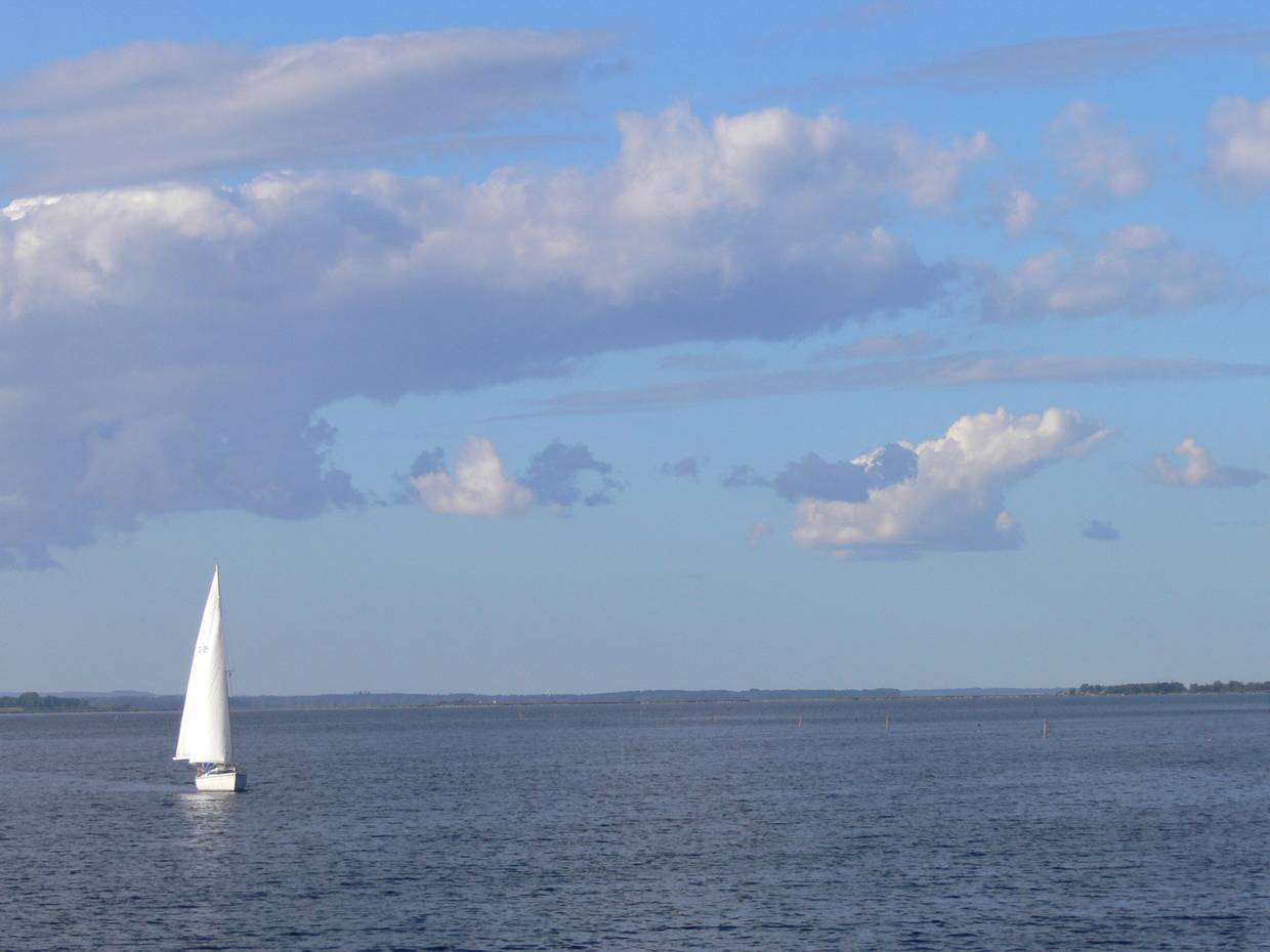 Großer See mit einem einzelnen Segelboot in der Mitte