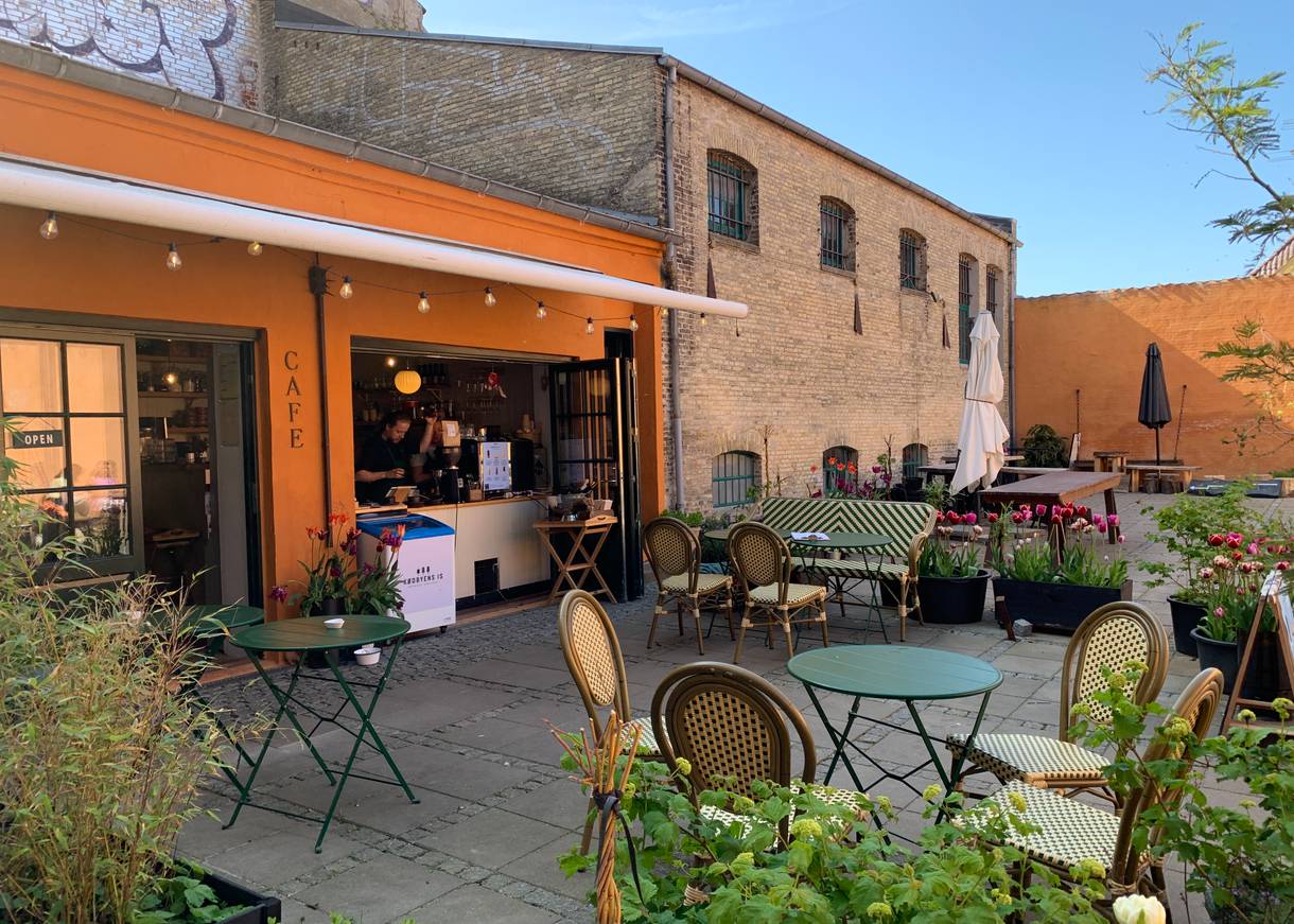 Hinterhof mit einem Restaurant, davor Bistrotische für die Gäste