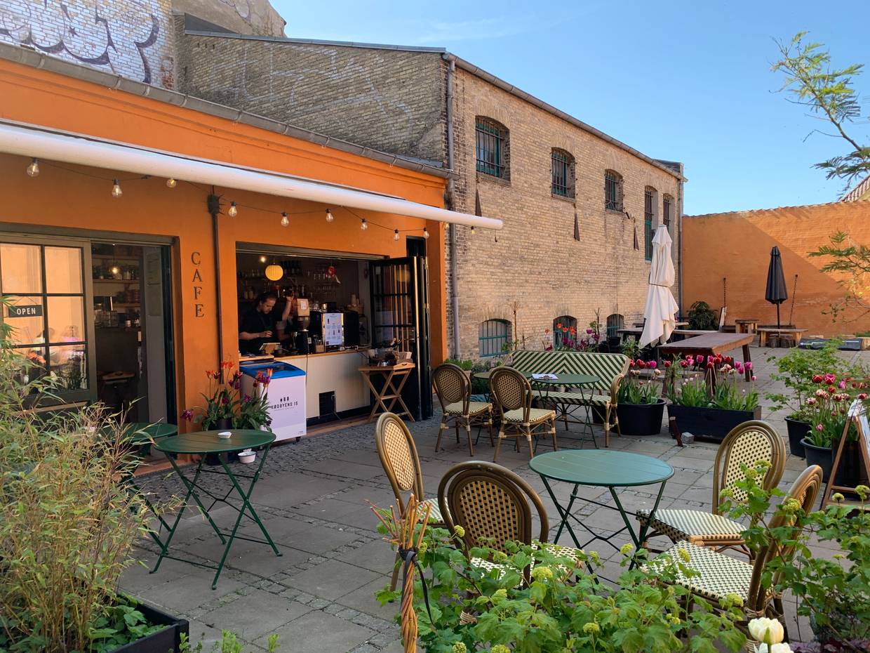 Hinterhof mit einem Restaurant, davor Bistrotische für die Gäste