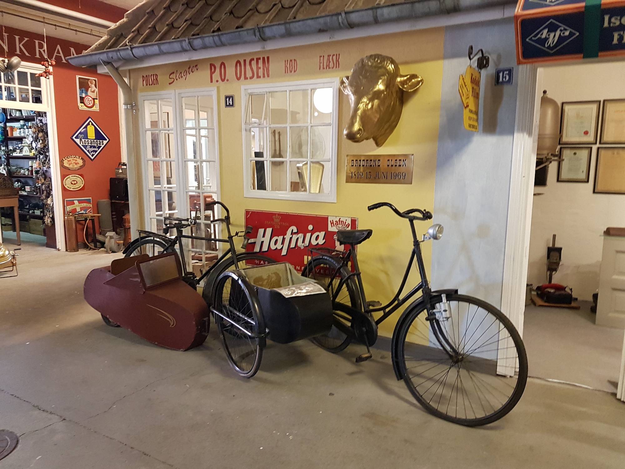 Helle Museumsräume mit einem alten Fahrrad, dahinter ein Kramerladen