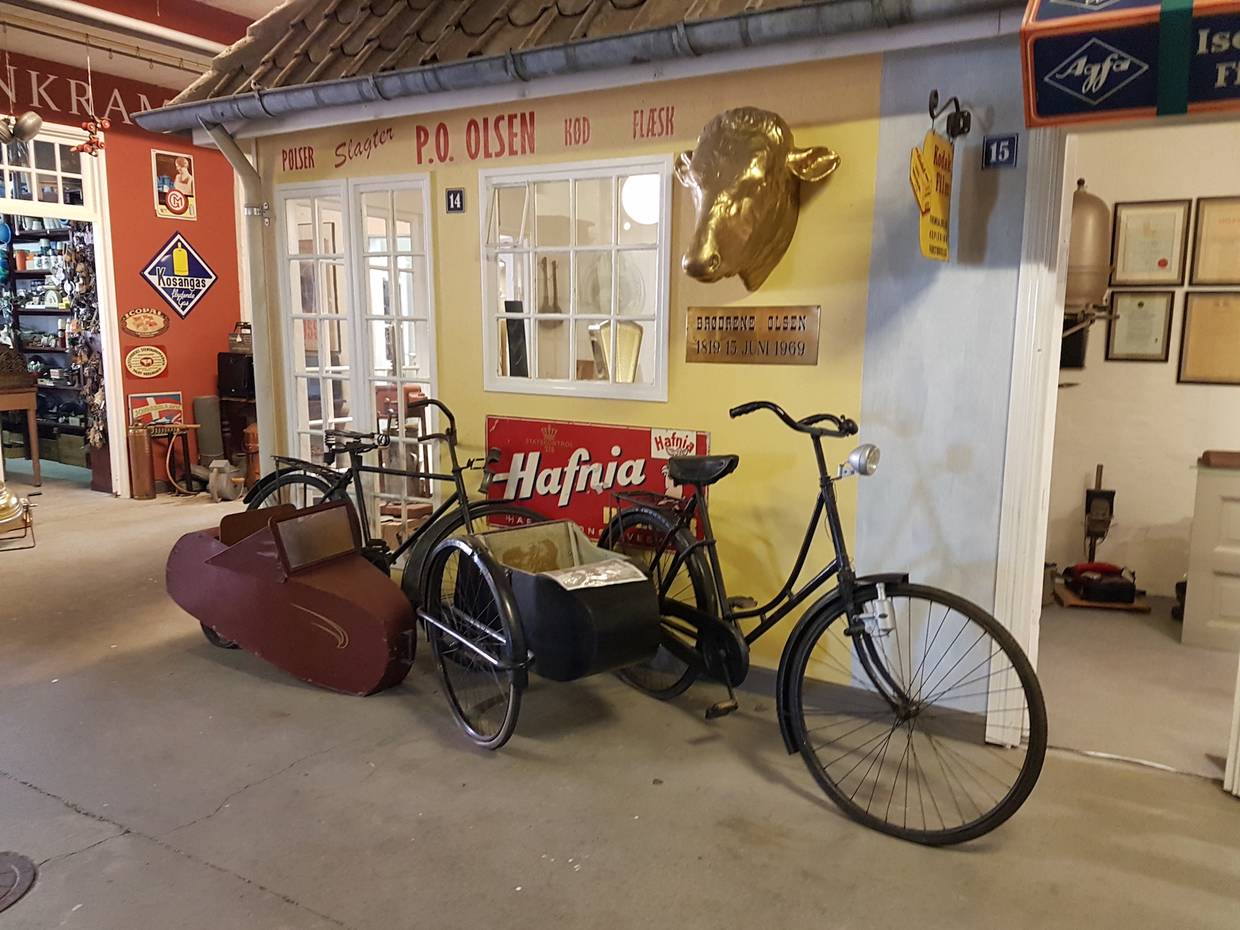 Helle Museumsräume mit einem alten Fahrrad, dahinter ein Kramerladen