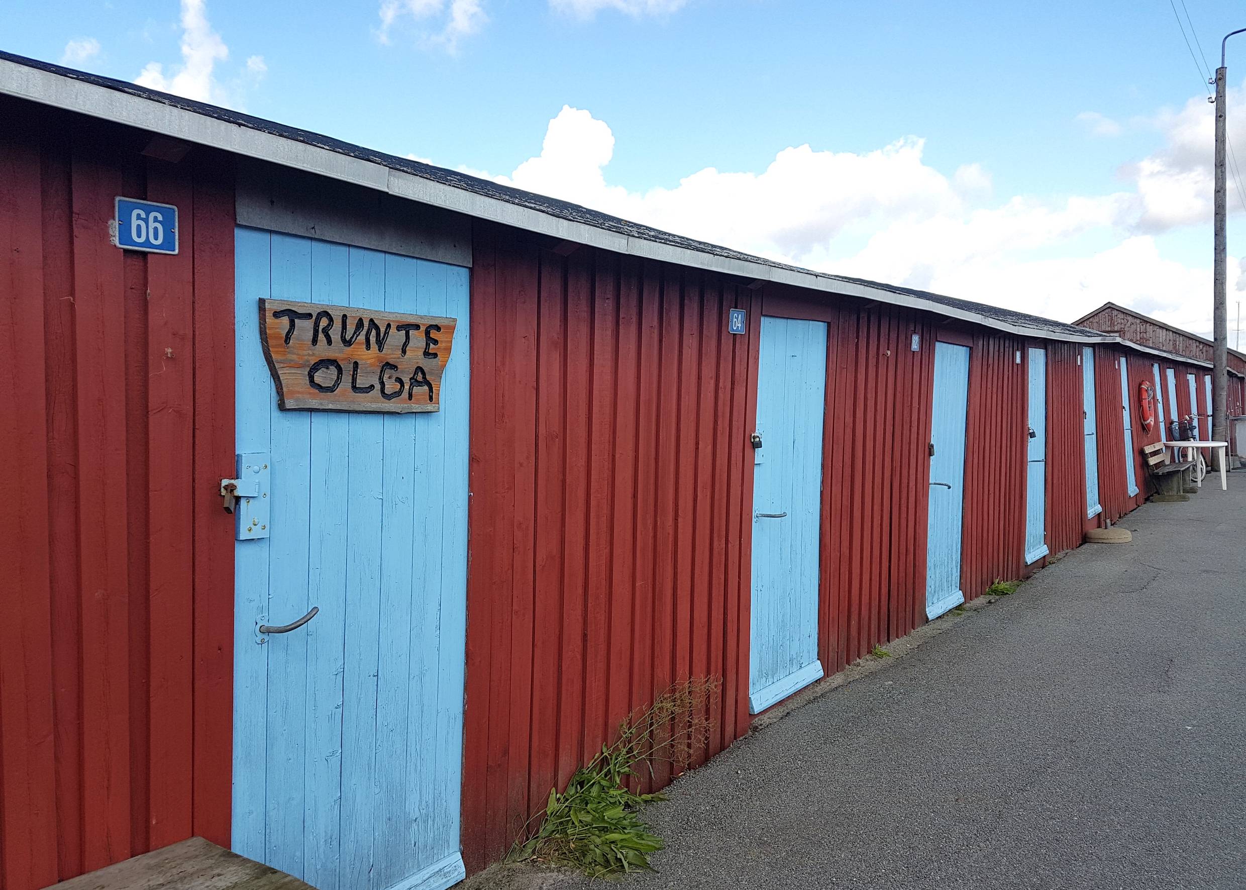 Langes, rotes Holzgebäude mit hellblauen Türen
