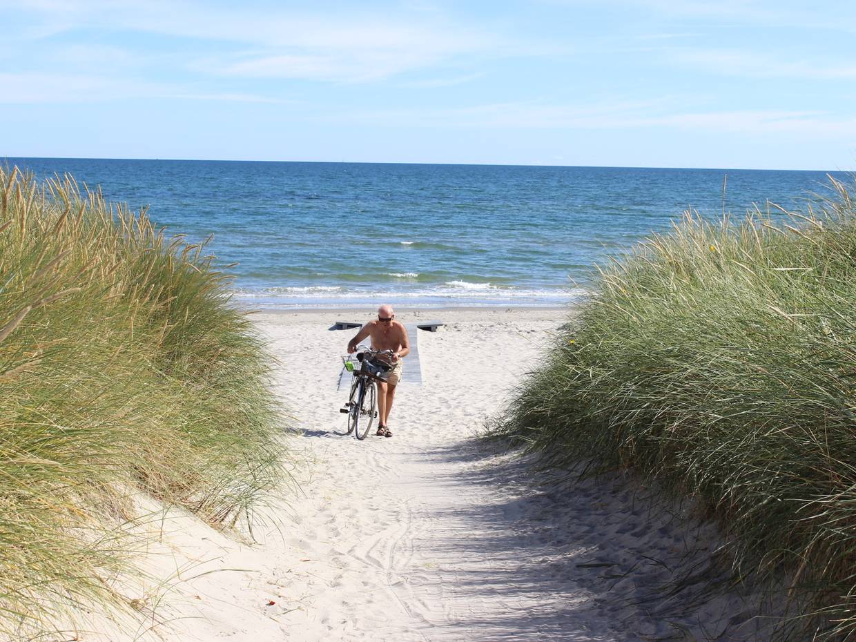 Ein Mann schiebt sein Rad auf den Strand