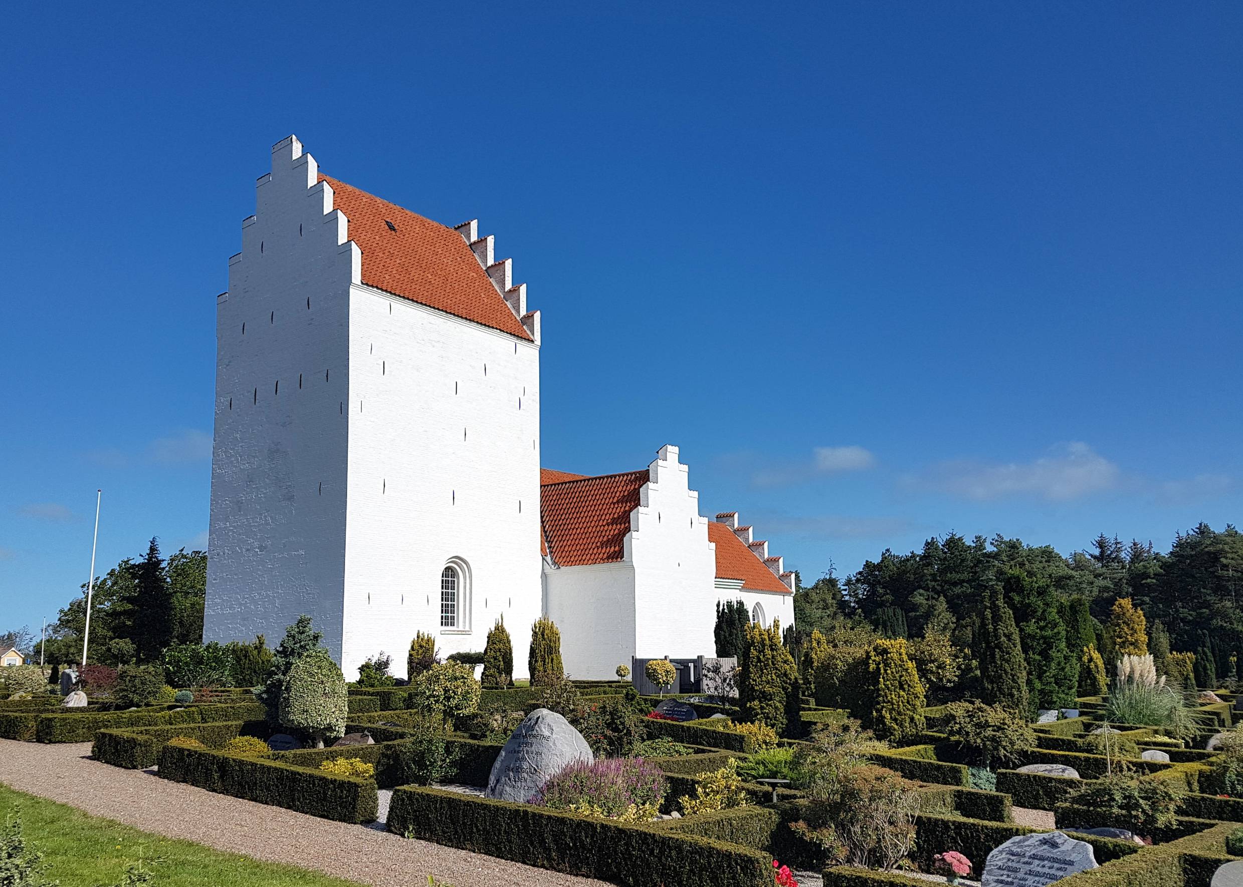Weiße, dänische Kirche, umgeben von einem Friedhof