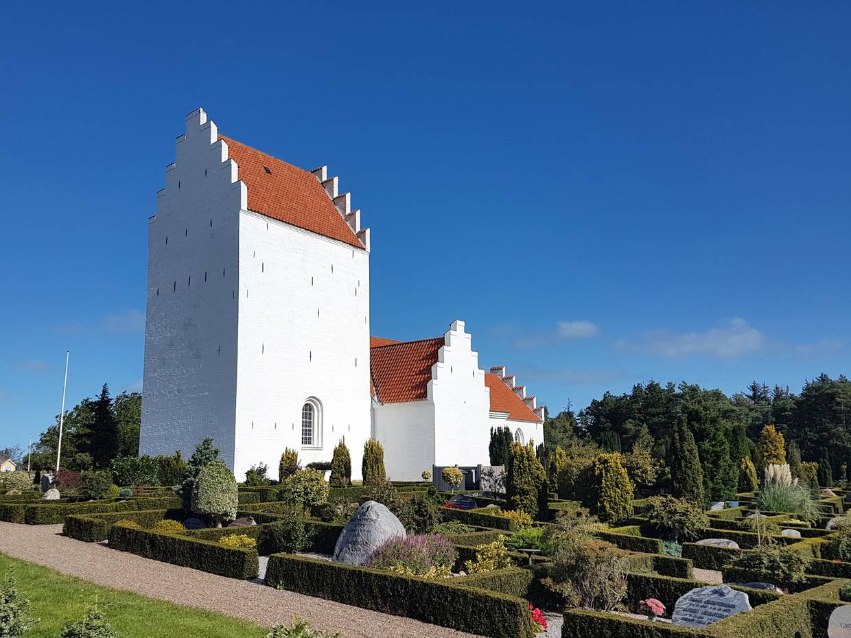 Weiße, dänische Kirche, umgeben von einem Friedhof