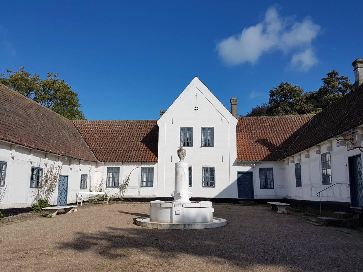 Weißer Gutshof um einen Innenhof mit Brunnen