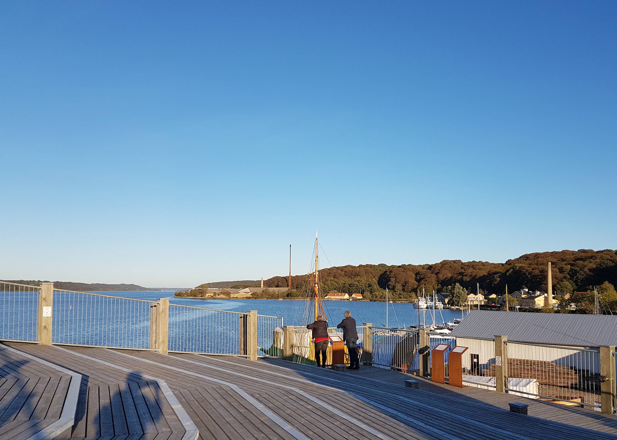 Ein Paar genießt die Aussicht von einer Holzterrasse über dem Fjord