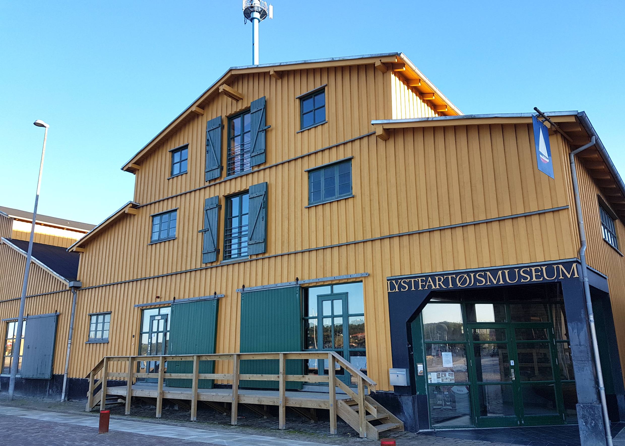 Gelbes Holzhaus mit grünen Fensterläden