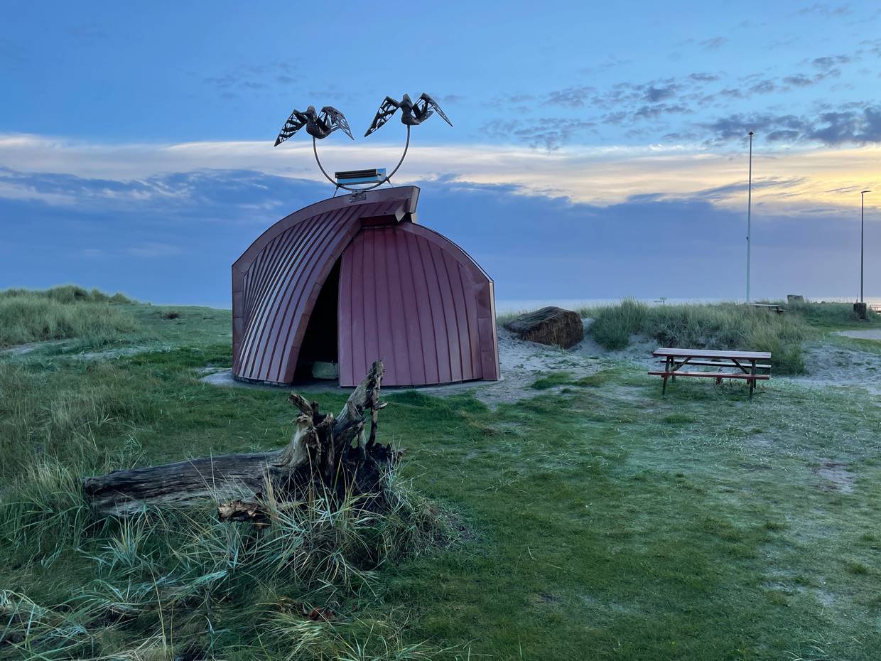 Skulptur aus zwei Bootshälften am Hafen Hou in der Abendsonne am Meer