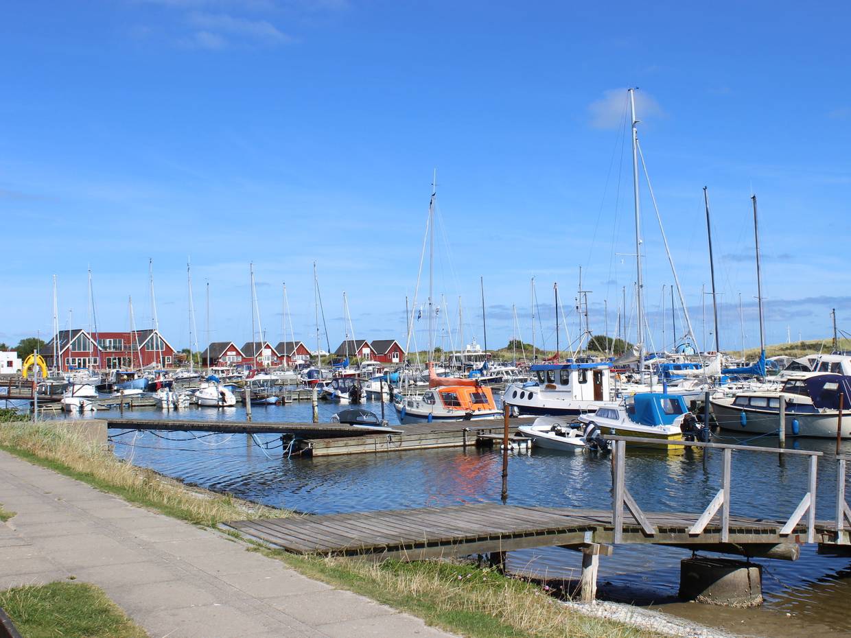 Segeljachten am Steg, dahinter rote Holzhäuser