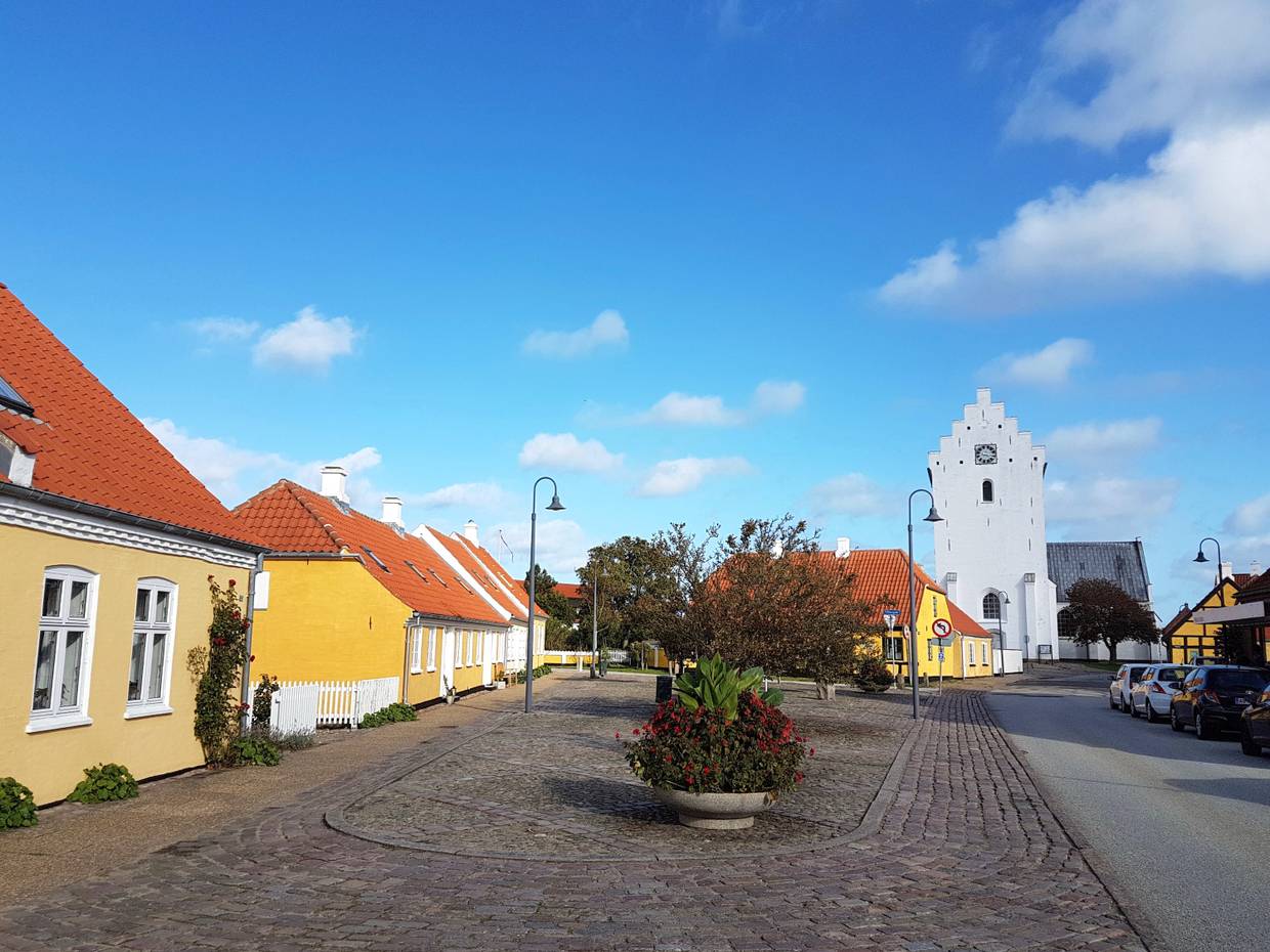 Kopfsteinpflastergasse mit gelben Häusern, dahinter der weiße Dom