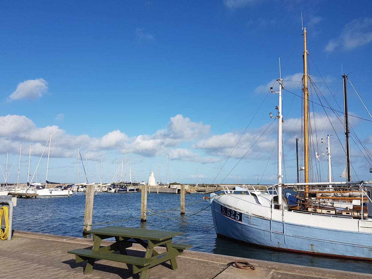 Hafenbecken mit Fischerboot, im Hintergrund eine weiße Skulptur