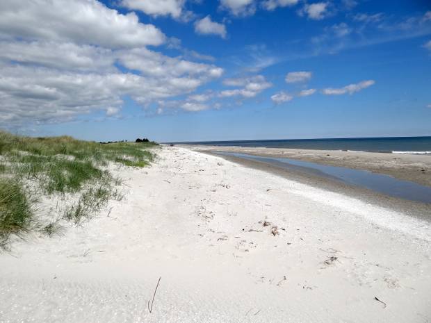 Aussicht von einer flachen Sandstrand über ein Ferienhausgebiet in einer Bucht
