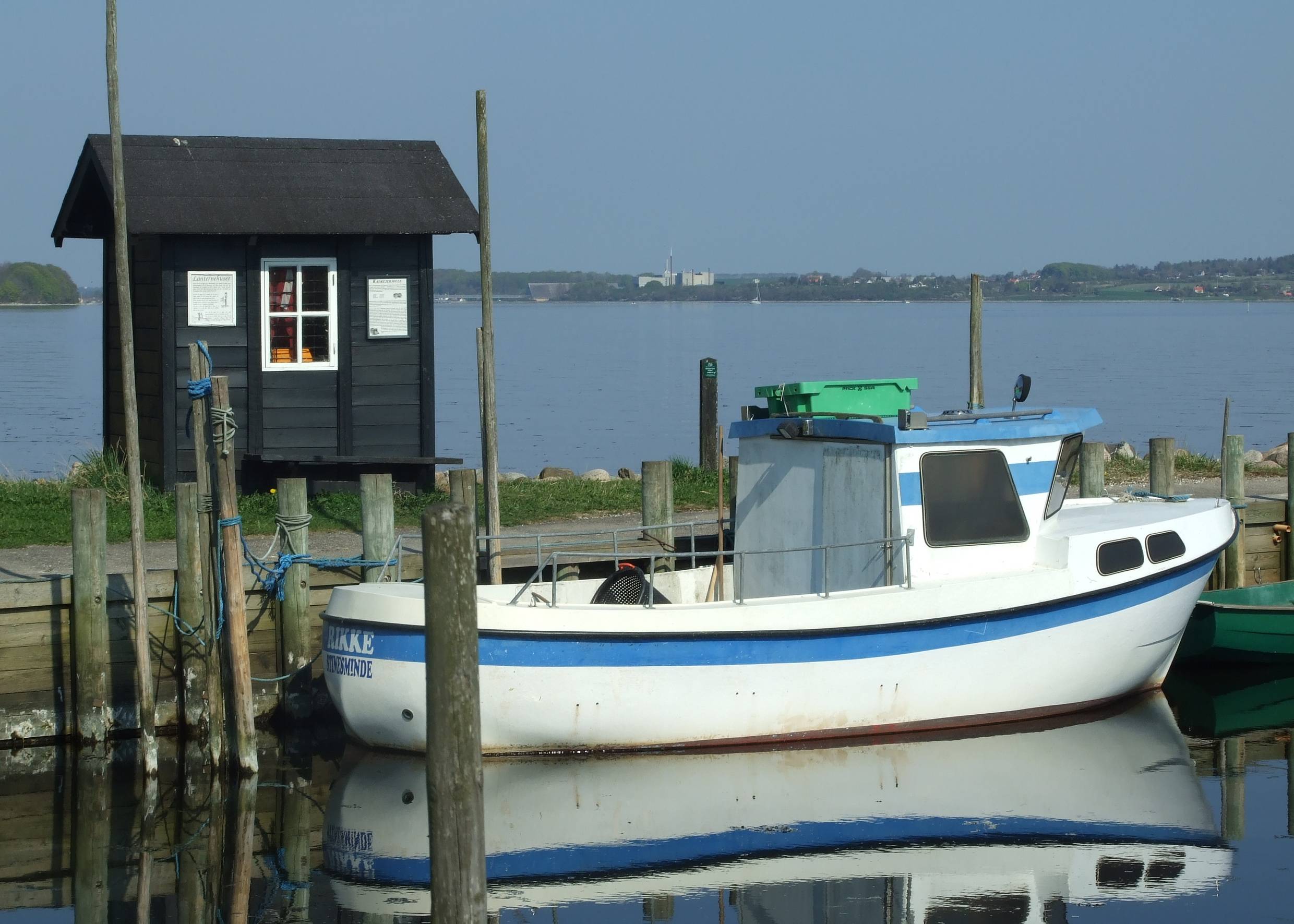 Blau-weißes kleines Boot vor einer winzigen Fischerhütte