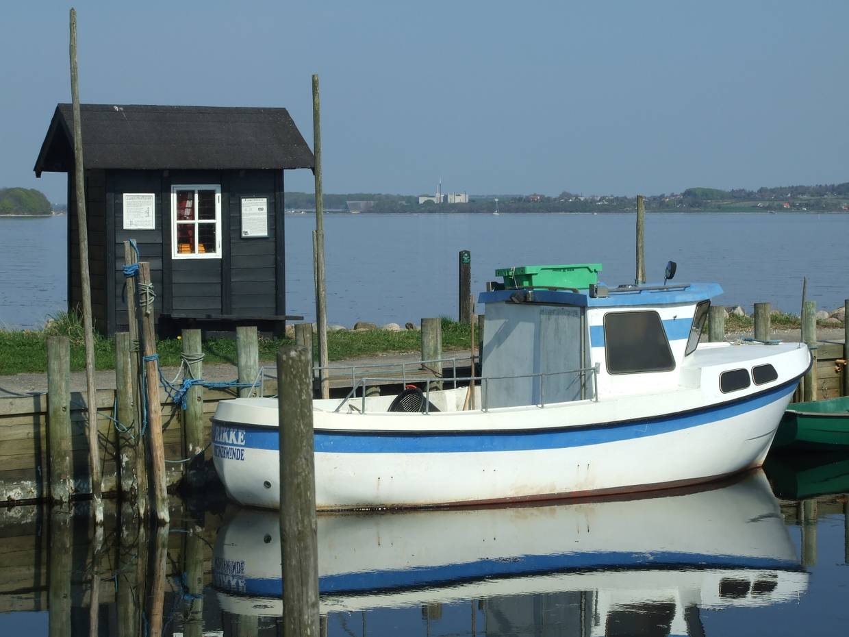 Blau-weißes kleines Boot vor einer winzigen Fischerhütte