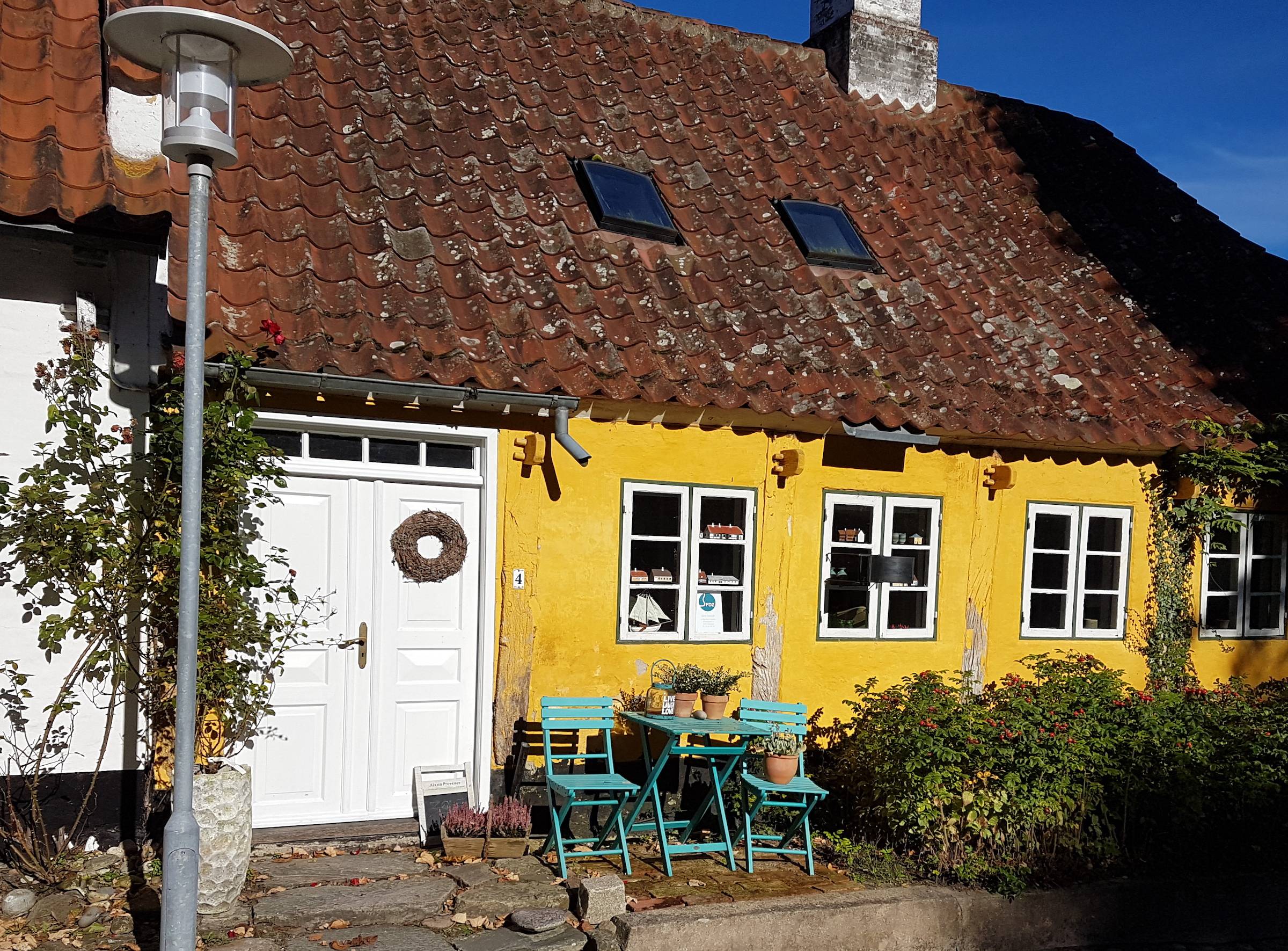 Gelbes altes Haus mit Sitzecke vor der Tür