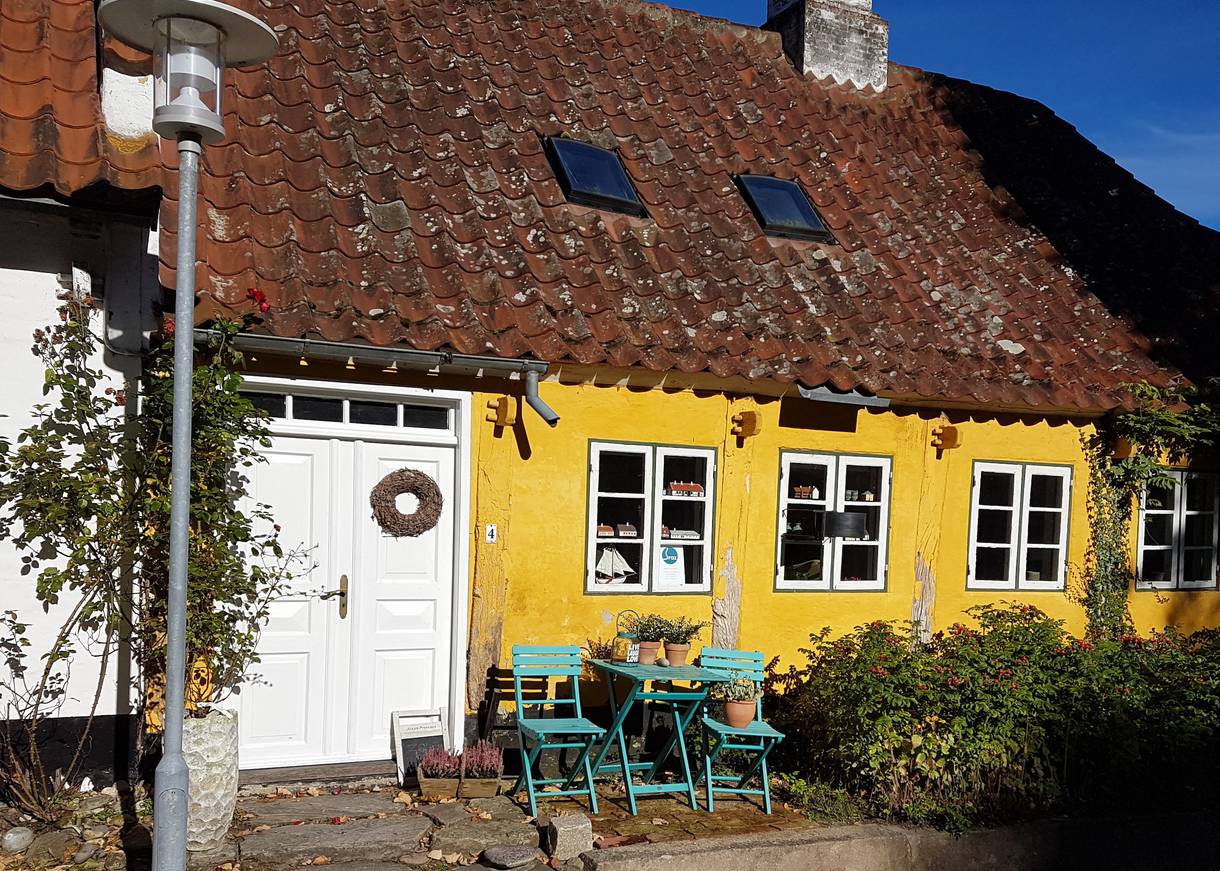 Gelbes altes Haus mit Sitzecke vor der Tür