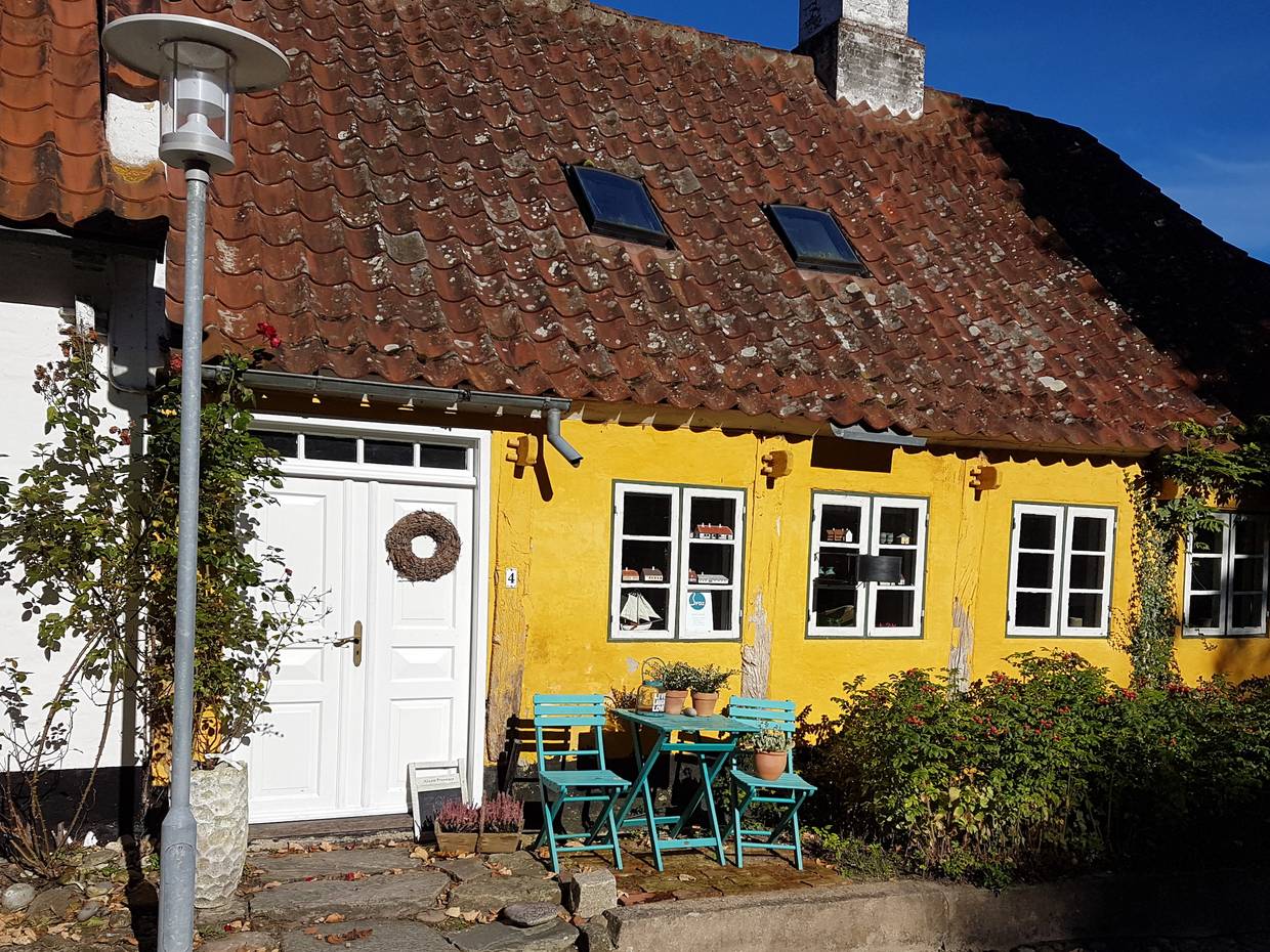 Gelbes altes Haus mit Sitzecke vor der Tür