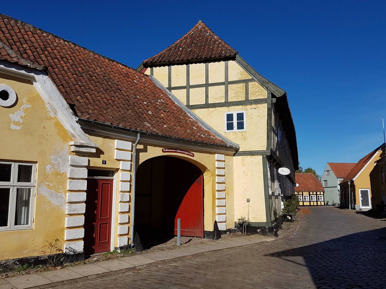 Gelbes Fachwerkhaus mit einer rot gestrichenen Hofeinfahrt