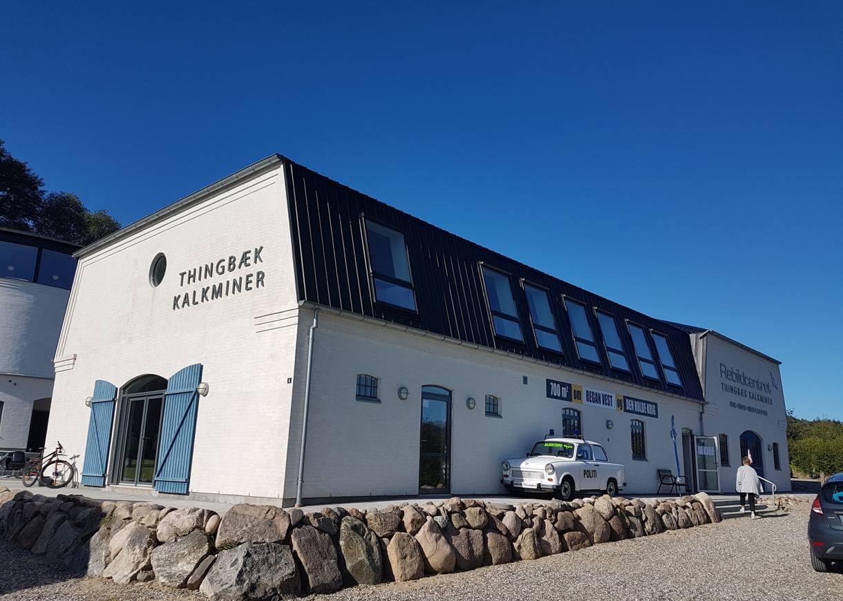 Weißes Eingangsgebäude zu einer Kalkmine, davor ein Trabbi