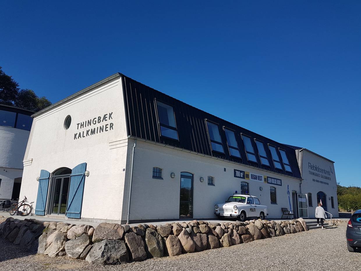 Weißes Eingangsgebäude zu einer Kalkmine, davor ein Trabbi