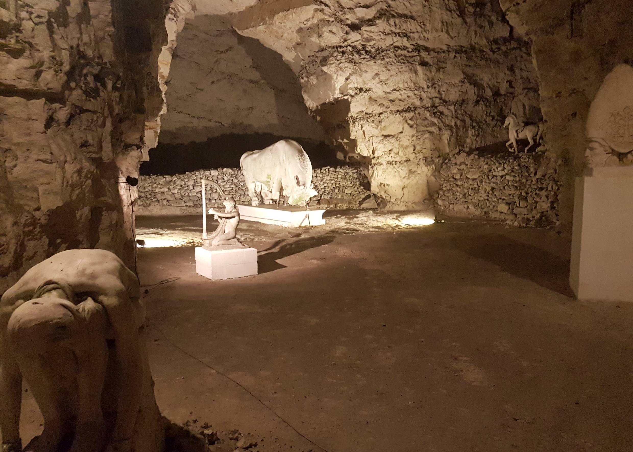 Blick in die beleuchtete Höhle auf weiße Gipsfiguren 