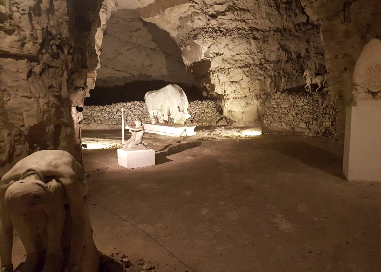 Blick in die beleuchtete Höhle auf weiße Gipsfiguren 