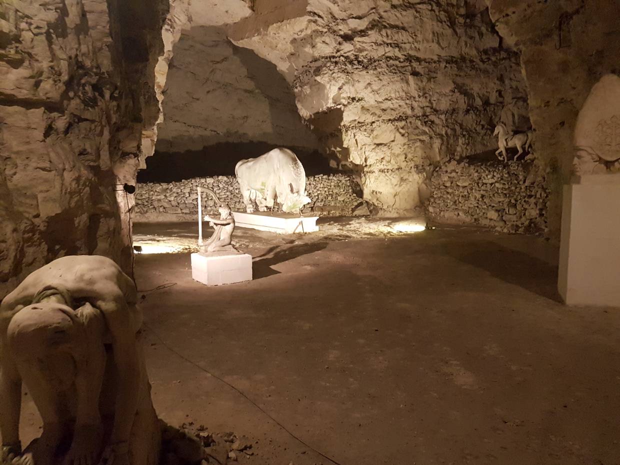 Blick in die beleuchtete Höhle auf weiße Gipsfiguren 