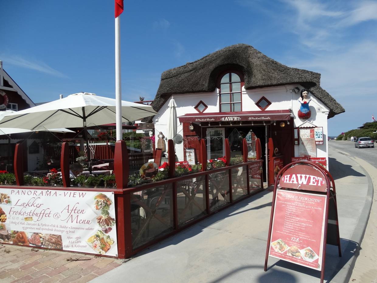 Bistroterrasse vor einem rot-weißen Reetdachhaus