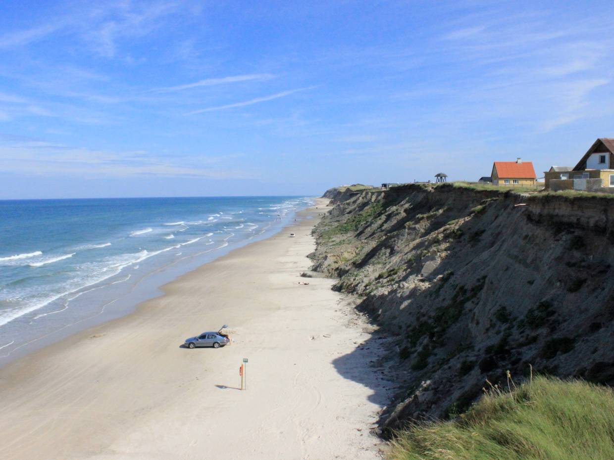 Steilküste in Nr. Lyngby mit einzelnen Häusern und einem Auto am Strand