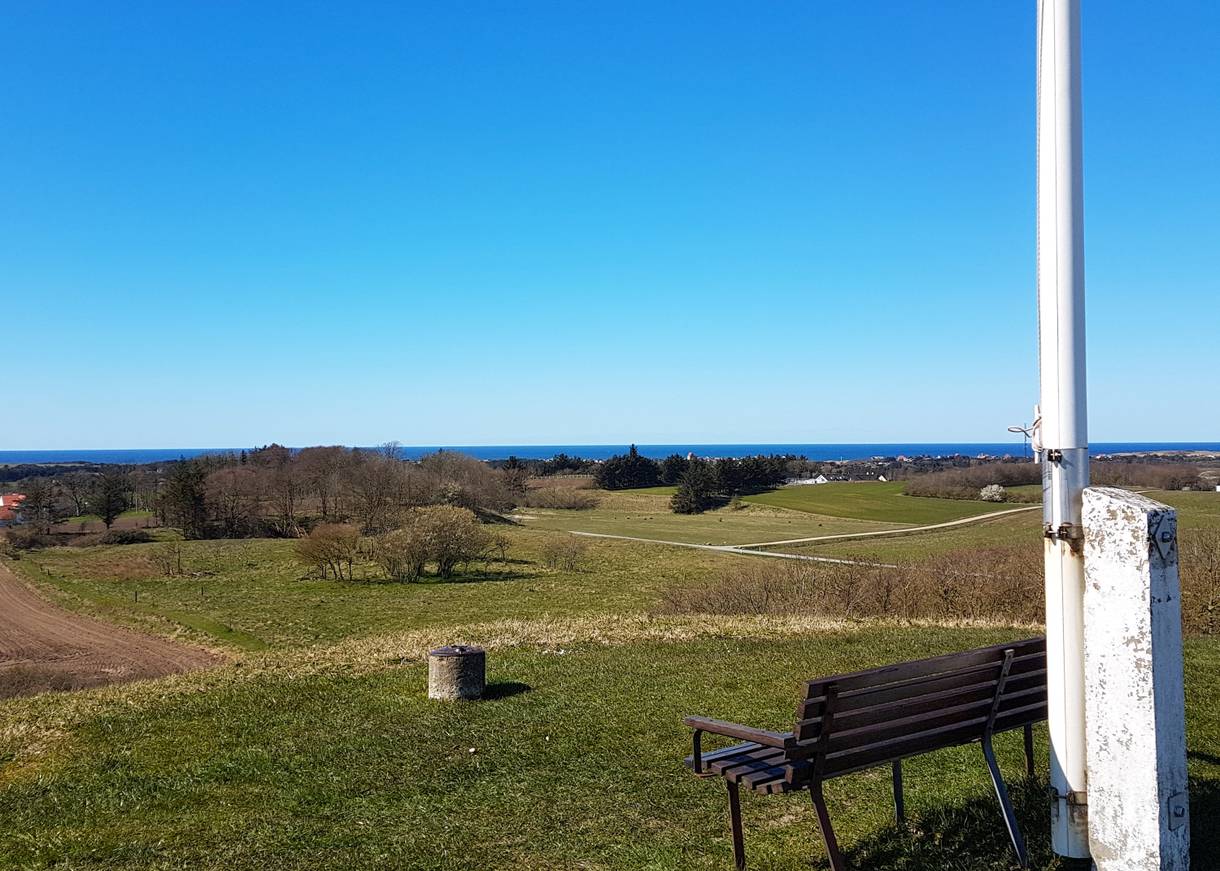 Bank neben einem Fahnenmast mit Blick über die Landschaft zur Nordsee