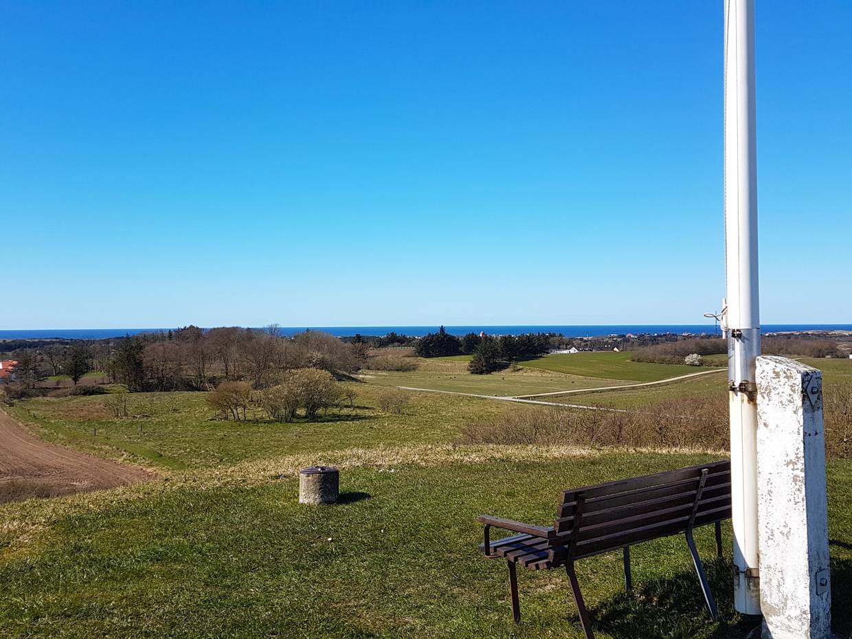 Bank neben einem Fahnenmast mit Blick über die Landschaft zur Nordsee