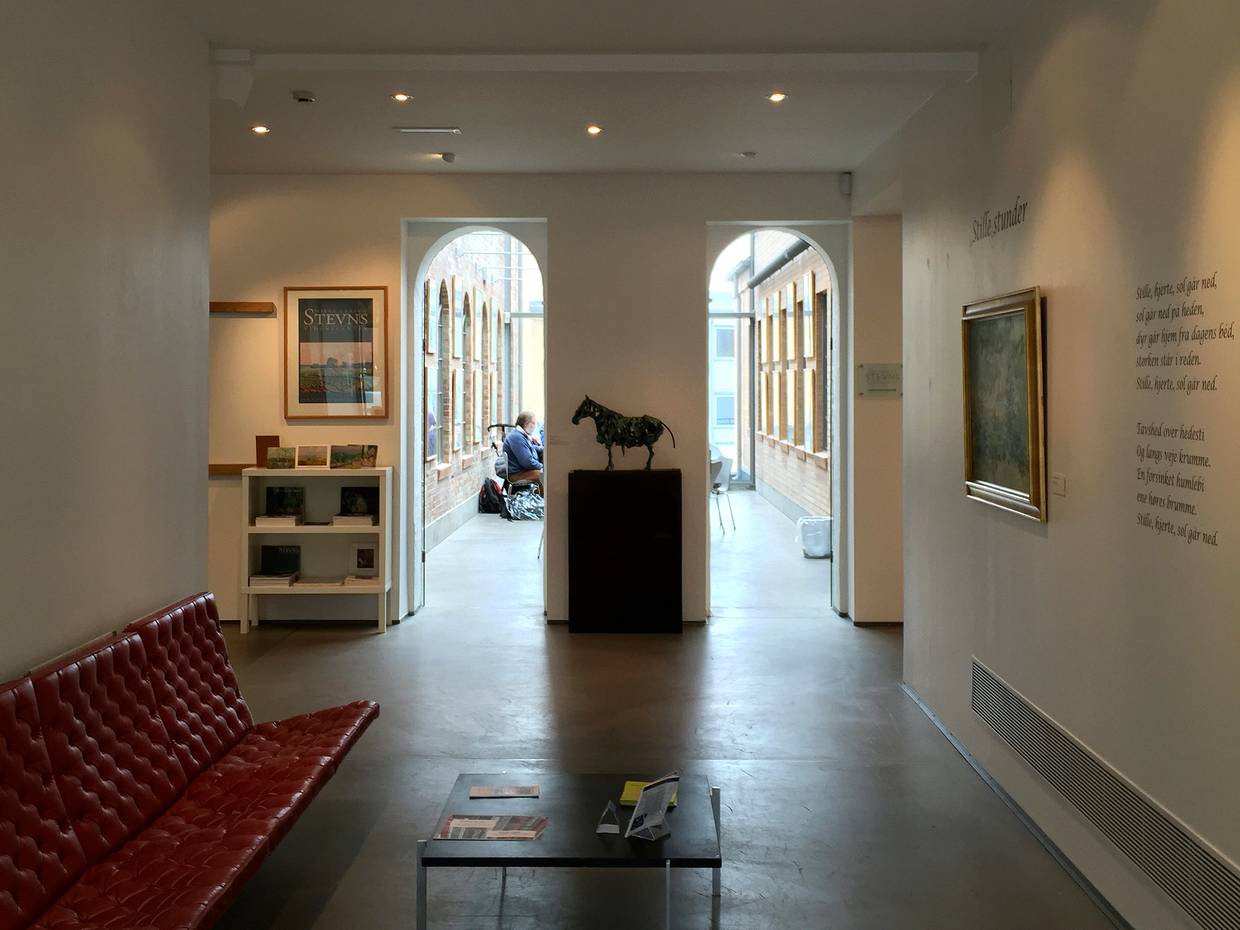 Eingang im Museum, ein roter Ledersitz und eine Skuptur von einem Pferd 