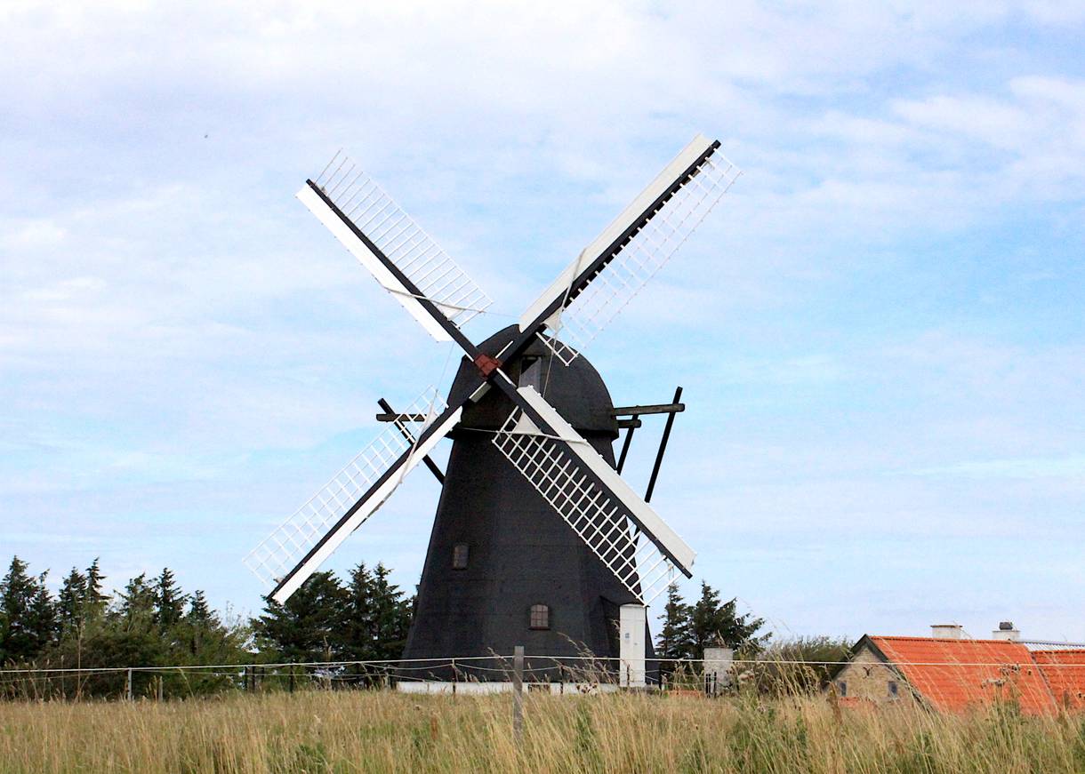 Große schwarze Windmühle vor blauem Himmel