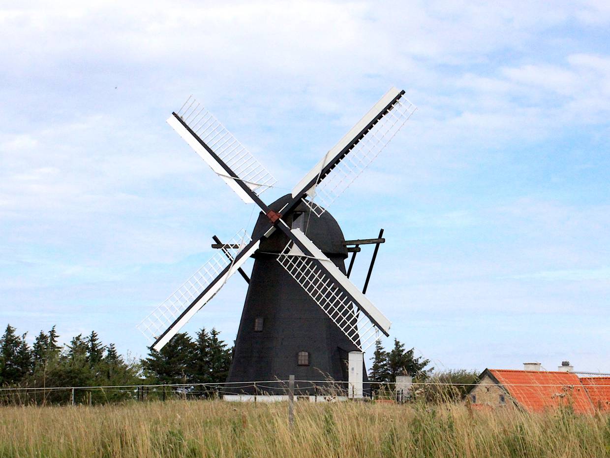 Große schwarze Windmühle vor blauem Himmel