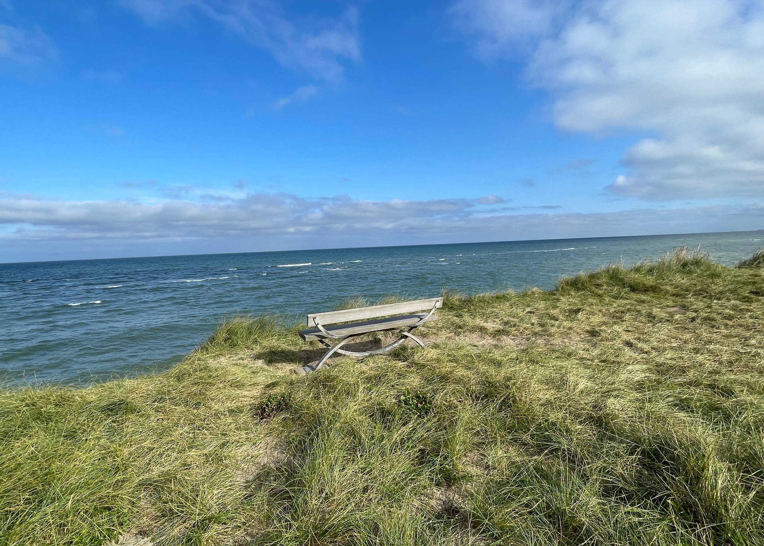 Holzbank am Rande einer Steilküste mit Meeresblick