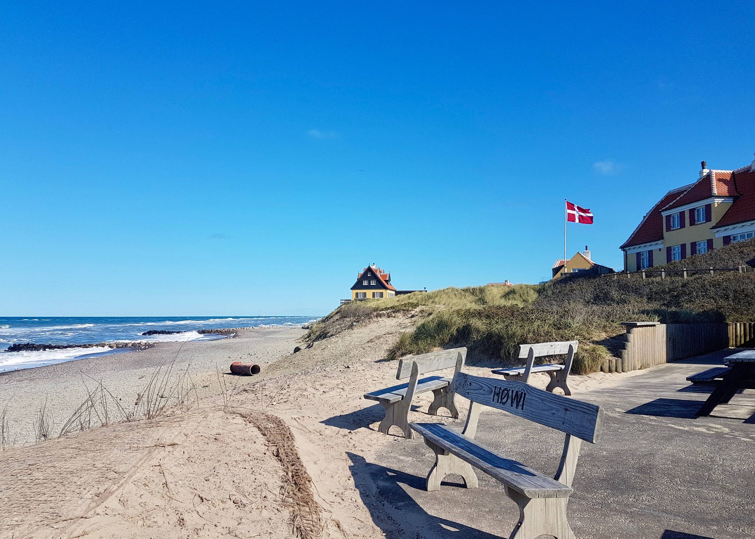 Rund gepflasterter Platz mit mehreren Bänken direkt am Strand